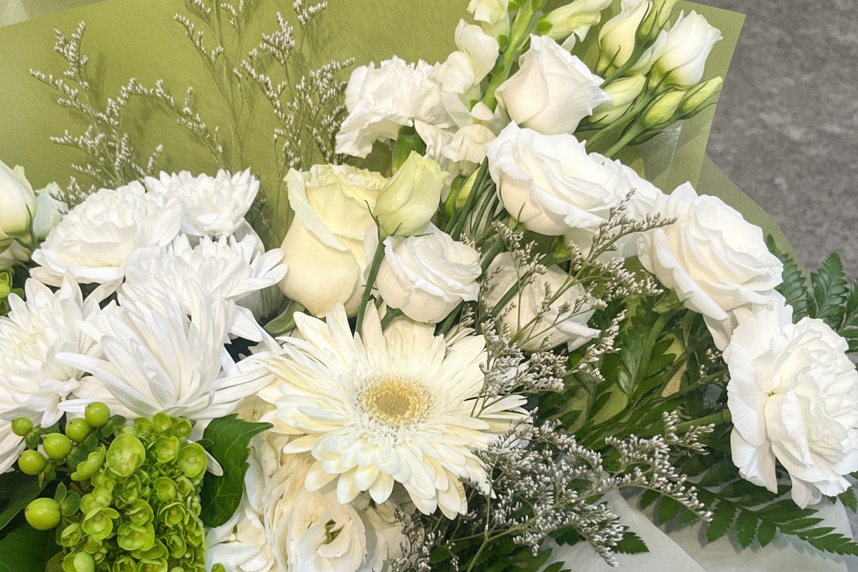 Bouquet of white flowers including roses and daisies on a green fabric background